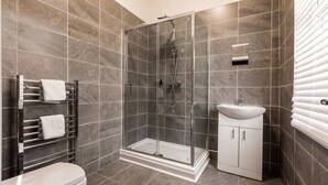 Ein modernes Badezimmer mit einer Duschkabine aus Glas, einer weißen Toilette und einem Waschbecken mit Schrank.