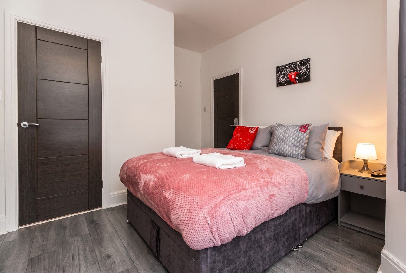 A bedroom with a bed, bedside table, and a door.