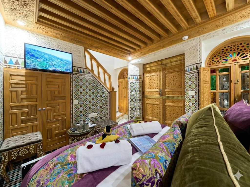A room with a bed, a television, a wooden wardrobe, and a decorative cabinet.