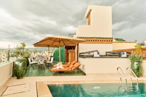 A rooftop pool area with lounge chairs, a table, and a covered seating area. - Riad May Fes Original & Spa (Fès)