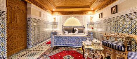 A room with intricate tile work, a patterned carpet, and a bed with a blue and white design.