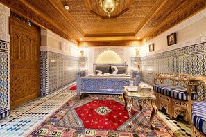 A room with intricate tile work, a patterned carpet, and a bed with a blue and white design. - Riad May Fes Original & Spa (Fès)