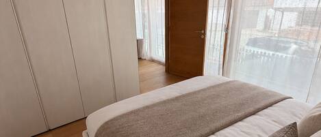 Une chambre avec un grand lit, un plafond en bois et une vue sur l’extérieur.