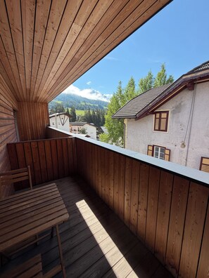 Ein Holzbalkon mit Blick auf Berge und Gebäude.