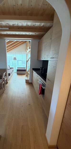 Eine moderne Küche mit Holzschränken, einer schwarzen Arbeitsplatte und einem roten Handtuch.
