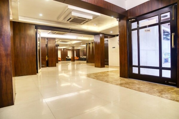 A hotel lobby with a polished floor, wooden paneling, and a closed door with a 'CLOSE' sign. - OYO Premium Rowland Road (Kolkata)