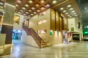 Un vestíbulo de hotel con una escalera, una recepción y un estacionamiento.