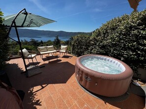 A hot tub with a view of a lake, outdoor furniture, and a patio area. - La Terrazza sul Lago -lake Peace - Wonderful View (Castel Gandolfo)