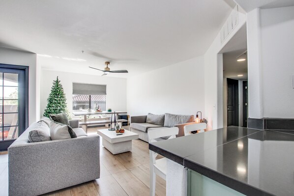 A modern living room with a sofa, coffee table, and a small Christmas tree.