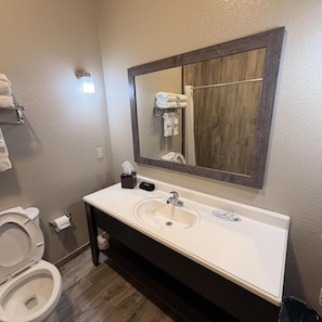 A bathroom with a white sink, a mirror, a toilet, and a towel rack.