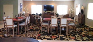 A living room with a dining area, a flat-screen TV, and a patterned carpet.