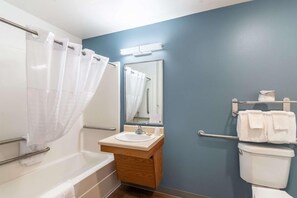A bathroom with a bathtub, sink, mirror, and towel rack. - Value Place Beaumont, TX (Beaumont)