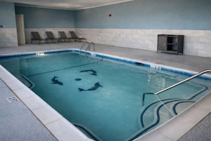 Una piscina con un borde empedrado, sillas de descanso y un armario pequeño.