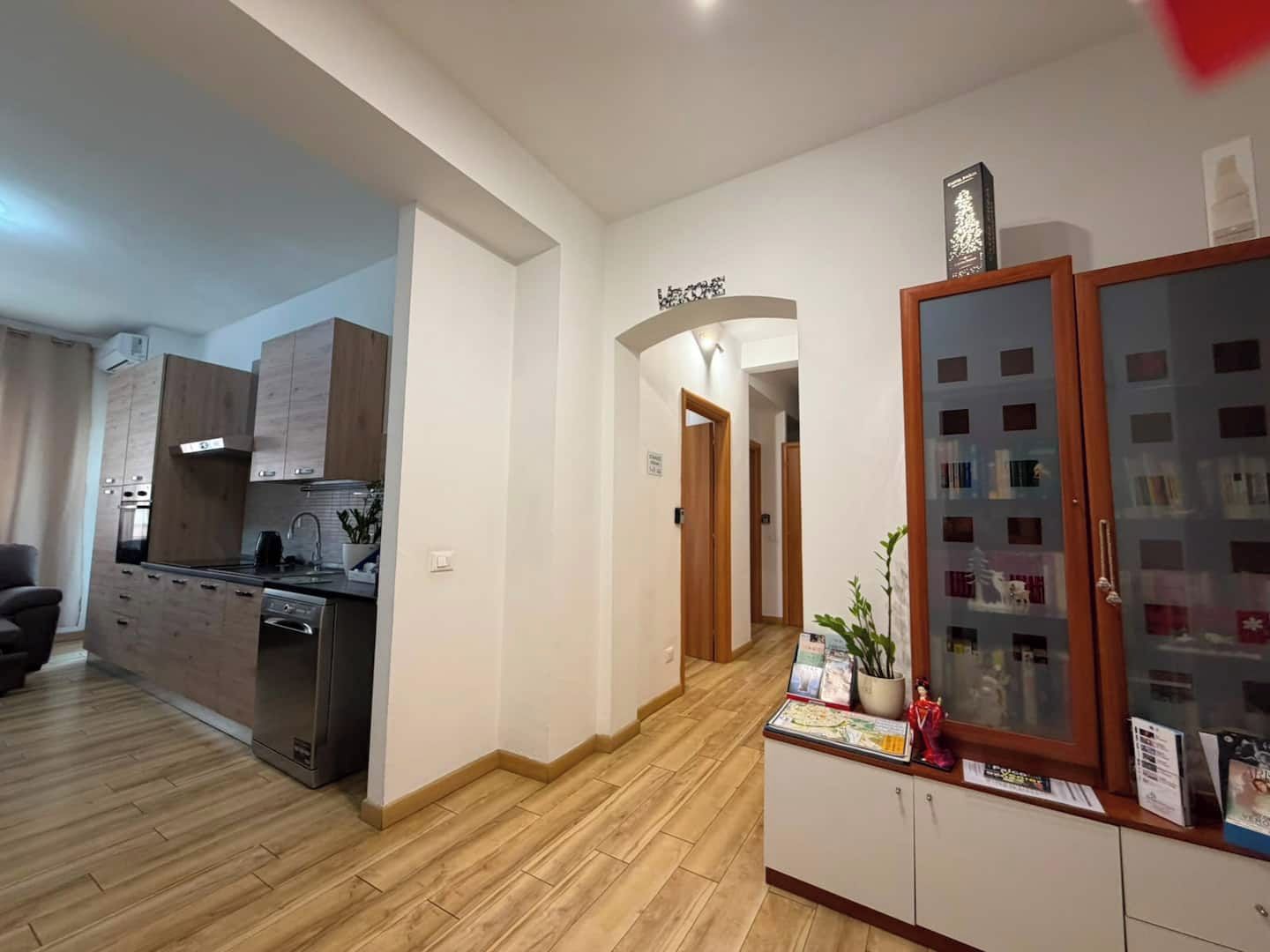 A modern apartment with a kitchen, a living area, and a hallway leading to another room.