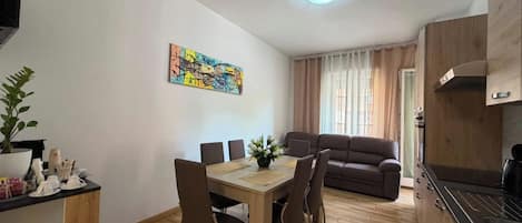 A modern living space with a dining area, a sofa, and a kitchen.