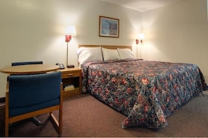 A hotel room with a bed, a desk, and a chair. There are two bedside lamps and a painting on the wall. - Americas Best Value Inn-winona/tyler (Tyler)