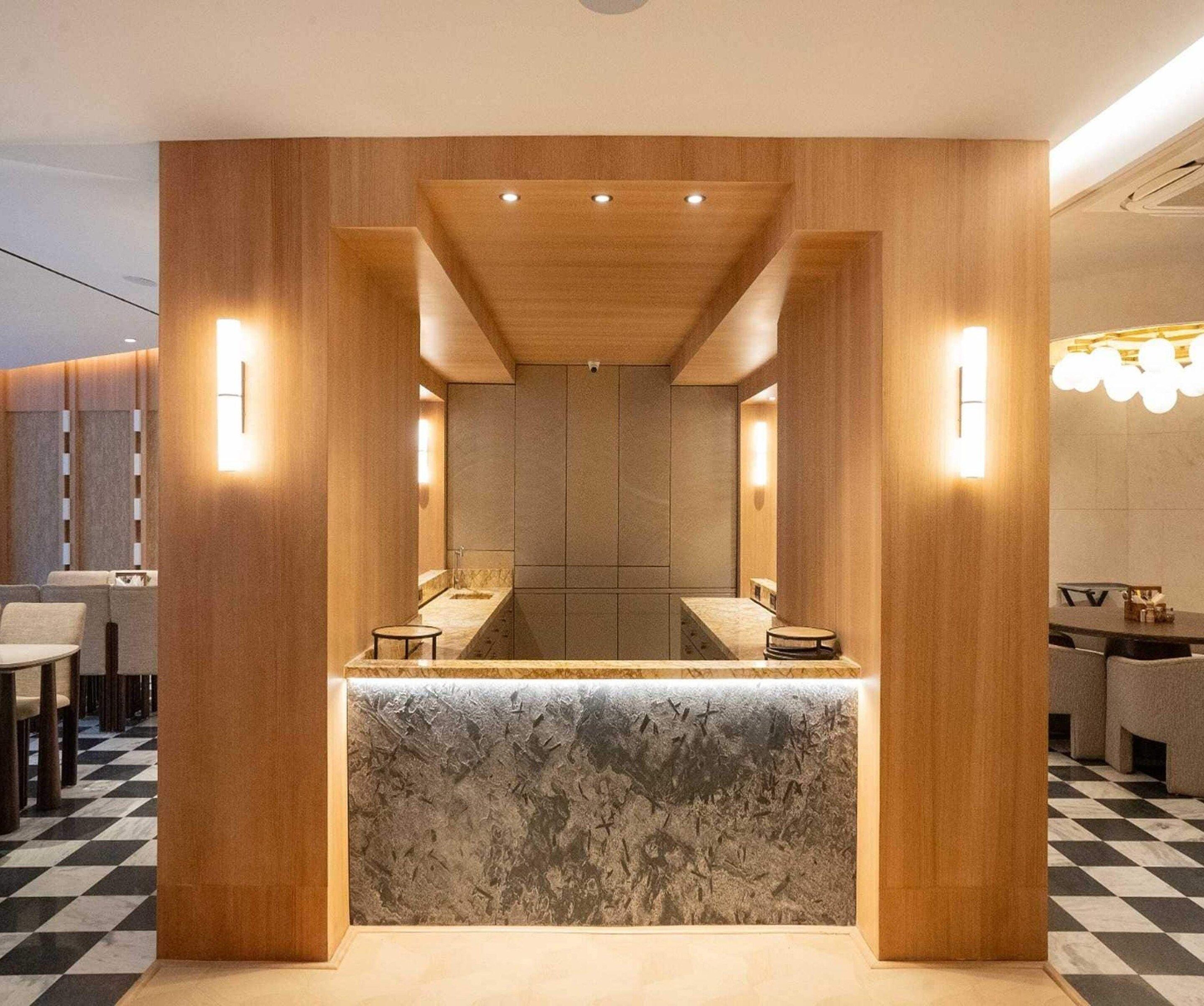 Un intérieur moderne avec un comptoir d’accueil central, des panneaux de bois et un sol à carreaux.