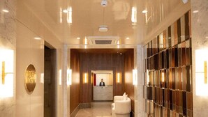 Um saguão de hotel com balcão de recepção, área de estar e parede com design padronizado.