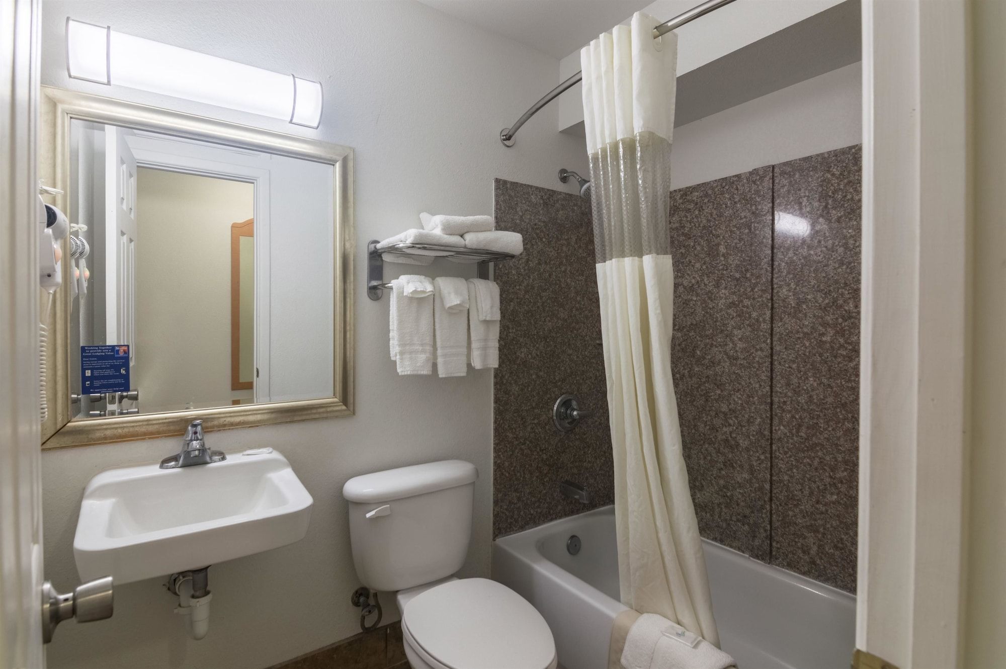 A bathroom with a sink, toilet, bathtub, and a shower curtain.