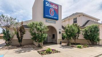 A hotel with a large sign reading 'Studio 6 Extended Stay.' There is a registration sign above the entrance, and the building has a beige facade with a flat roof.