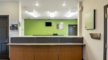 A reception area with a counter, a television mounted on the wall, and a sign indicating room number 6.
