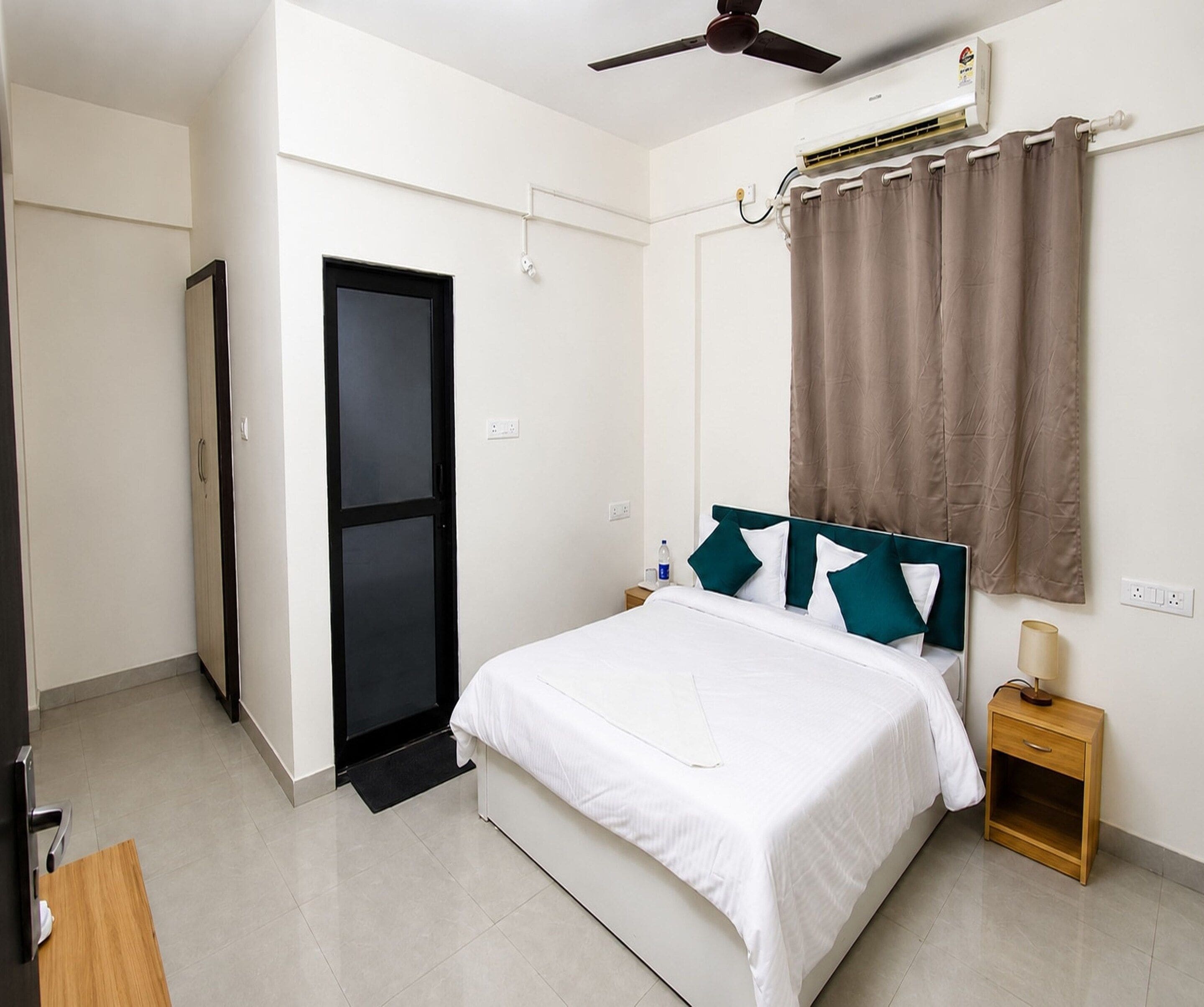A hotel room with a bed, bedside table, nightstand, and a ceiling fan.