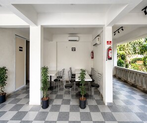 A dining area with tables and chairs, air conditioning units, a fire extinguisher, and potted plants. - Classic Phase-i Hinjewadi (Paud)