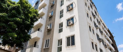 A multi-story residential building with balconies, air conditioning units, and a gated entrance.