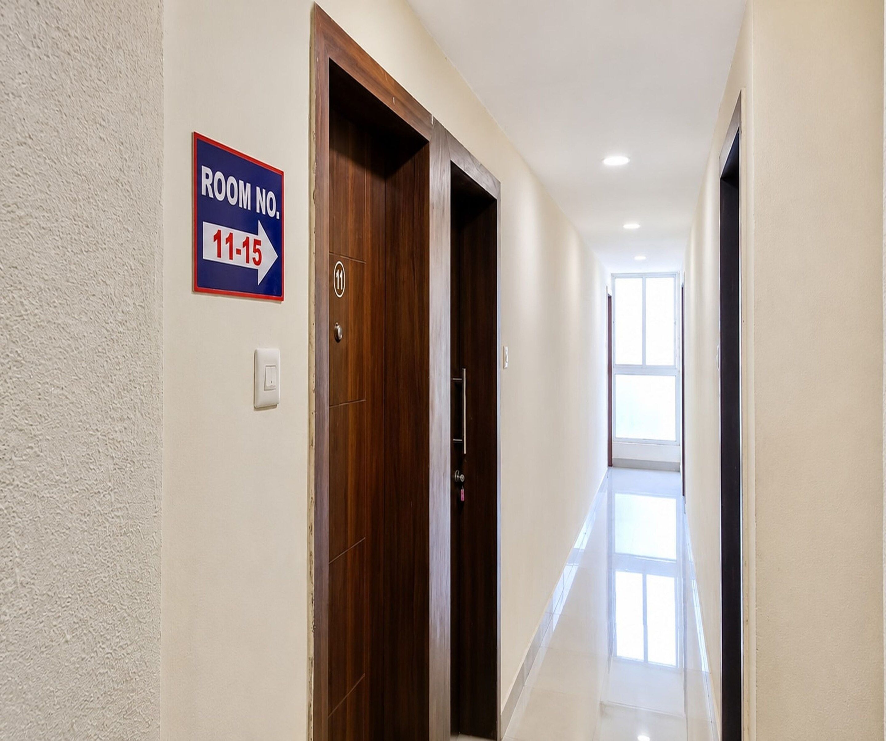A hotel hallway with a sign indicating room numbers 11-15.
