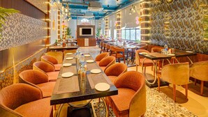 A restaurant with a long communal table, individual booths, and a patterned wall. - Classic Amar Resorrt (Motihari)