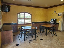 A kitchen with a dining area, a window with blinds, and a coffee machine.