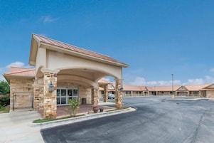 A hotel with a covered entrance, multiple rooms, and a parking lot.