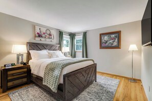 Een slaapkamer met een bed, nachtkastjes, een klok en kunstwerken aan de muur.