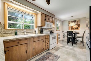 A kitchen with wooden cabinets, a microwave, a stove, and a dining area with chairs and a table. - Entire 3 bedroom house in Wallingford  CT with fully Stocked Kitchen (Wallingford)