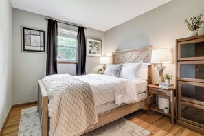 A bedroom with a bed, bedside tables, a nightstand, a lamp, a bedside plant, and a window with curtains. - Entire 3 bedroom house in Wallingford  CT with fully Stocked Kitchen (Wallingford)