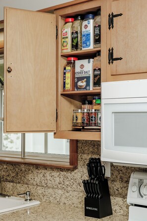 A kitchen with wooden cabinets, a white microwave, and a granite countertop.