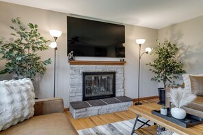 Een woonkamer met een stenen openhaard, twee vloerlampen, een bank en een salontafel.