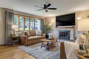 A living room with a sofa, coffee table, fireplace, and a television.