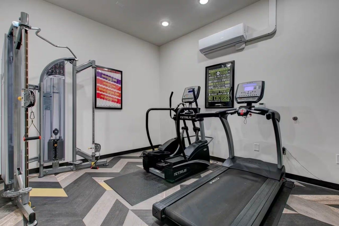 A gym with a treadmill, elliptical, and weight machine.