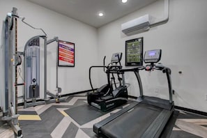 A gym with a treadmill, elliptical, and weight machine.