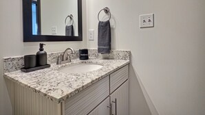 A bathroom with a marble sink, a black soap dispenser, a towel ring, and a mirror. - Two bedroom two bath, walk to UAB and dining (Birmingham)