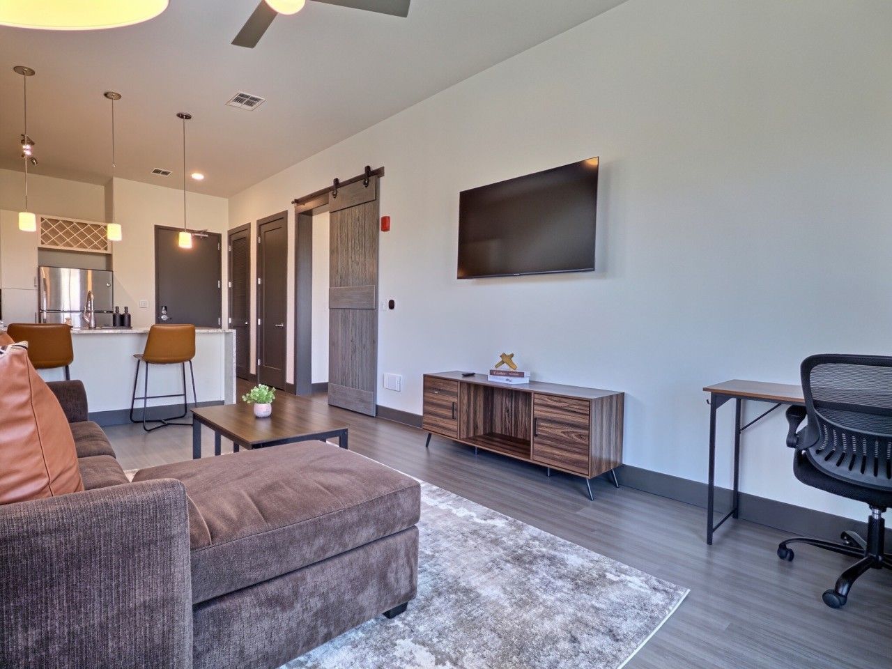 A modern living room with a sofa, coffee table, and a TV mounted on the wall.