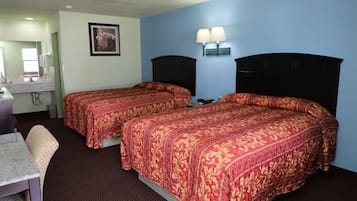 A hotel room with two beds, a desk, a chair, and a bathroom with a mirror.