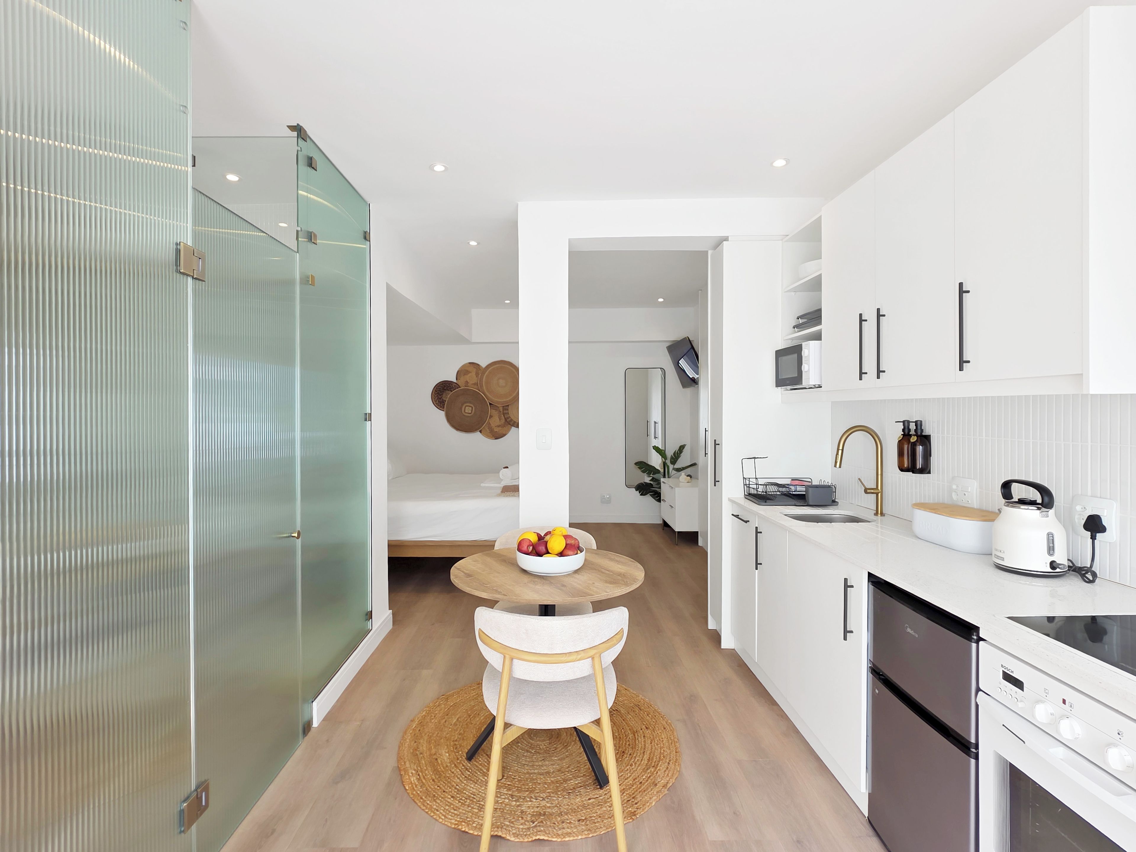 A modern kitchen with white cabinets, a stainless steel sink, and a Bosch refrigerator.