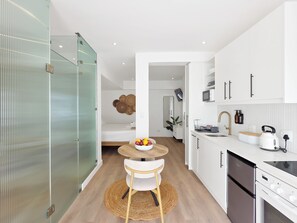 Eine moderne Küche mit weißen Schränken, einer Edelstahlspüle und einem Kühlschrank von Bosch.
