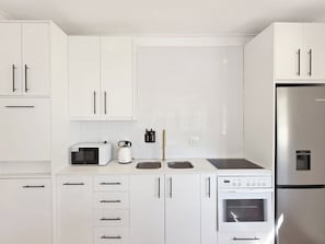 Una cucina moderna con mobili bianchi, un forno Bosch, un microonde e un frigorifero in acciaio inossidabile.