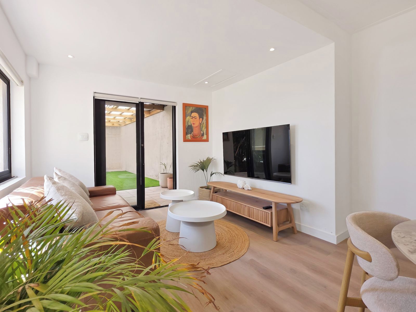 A modern living room with a sofa, coffee table, TV, and a sliding glass door leading to a balcony.