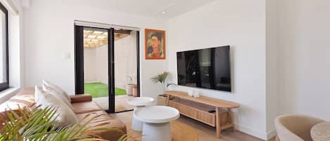 A modern living room with a sofa, coffee table, TV, and a sliding glass door leading to a balcony.