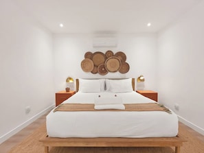 Una camera da letto con un letto grande, due comodini, un condizionatore d'aria a muro e un elemento decorativo sopra il letto.