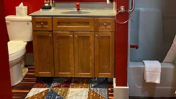 A bathroom with a wooden cabinet, a toilet, a sink, and a mirror.